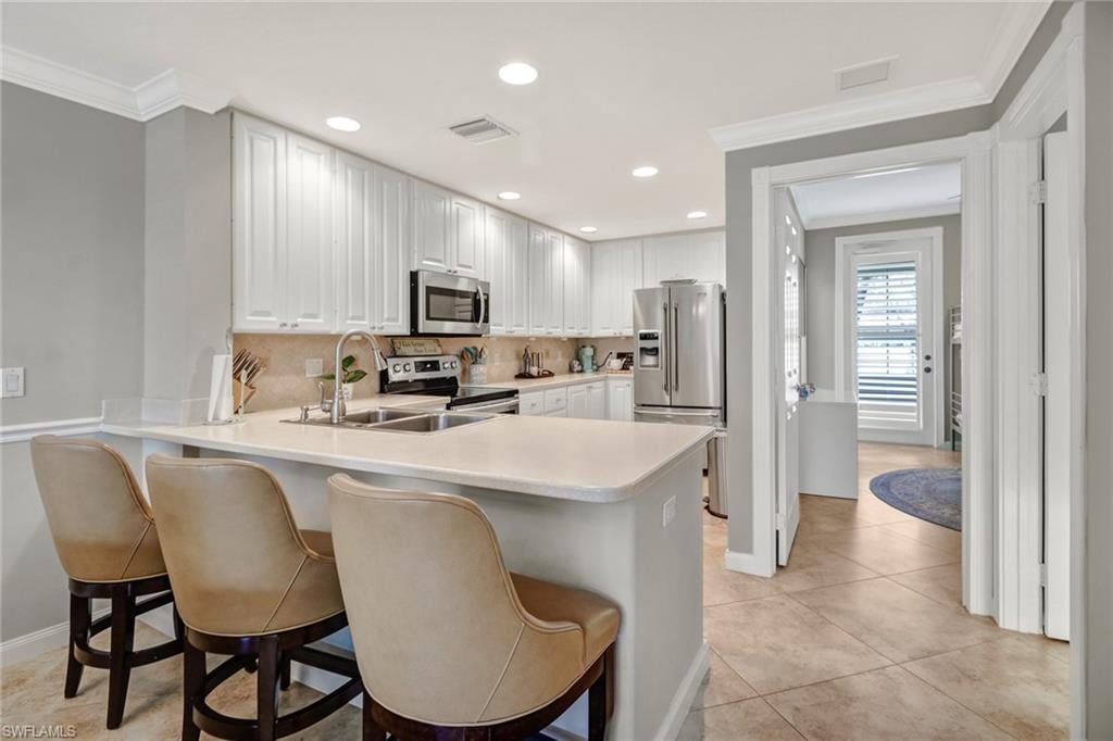 8028 Josefa Way Naples, FL 34114 - Photo 8 of 27 a kitchen with stainless steel appliances granite countertop a stove a sink a refrigerator a microwave oven with a dining table and chairs