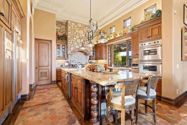 a kitchen with stainless steel appliances granite countertop a dining table chairs and a refrigerator
