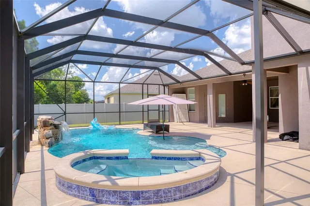an aerial view of a house with swimming pool and large trees