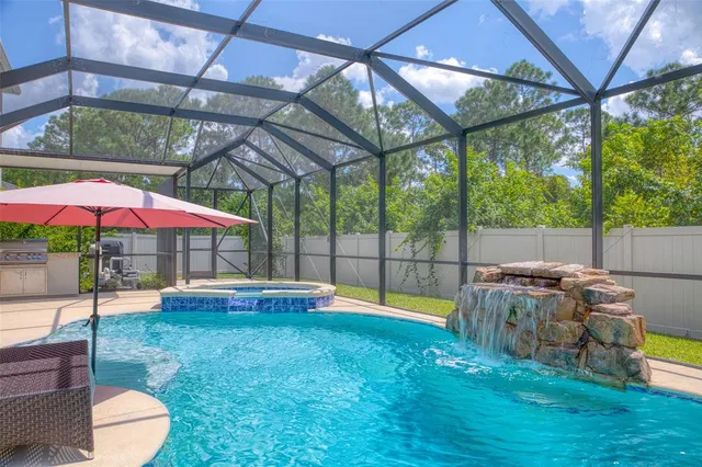 an aerial view of a swimming pool with a yard and seating area