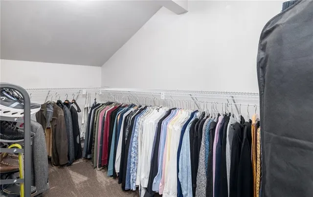 a view of walk in closet with clothes and shoes