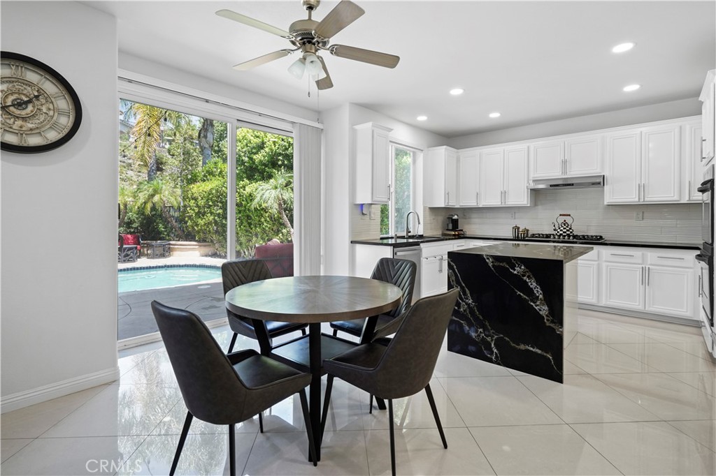 20621 Pesaro Way Porter Ranch, CA 91326 - Photo 14 of 45 a kitchen with a dining table chairs and white cabinets