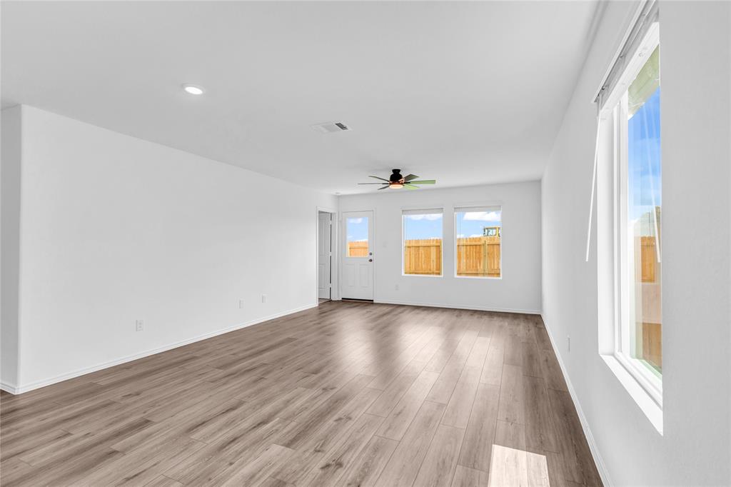 516 Rancho Del Cielo Loop Jarrell, TX 76537 - Photo 11 of 33 an empty room with wooden floor and windows