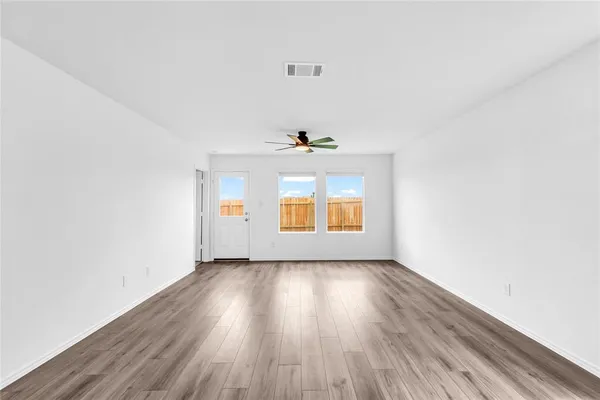 an empty room with wooden floor and windows