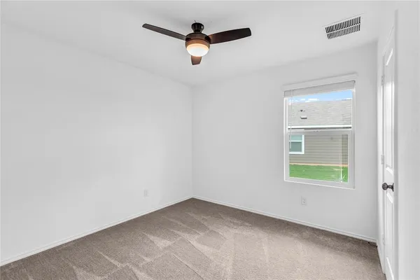 an empty room with windows and fan