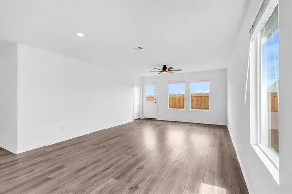 an empty room with wooden floor and windows