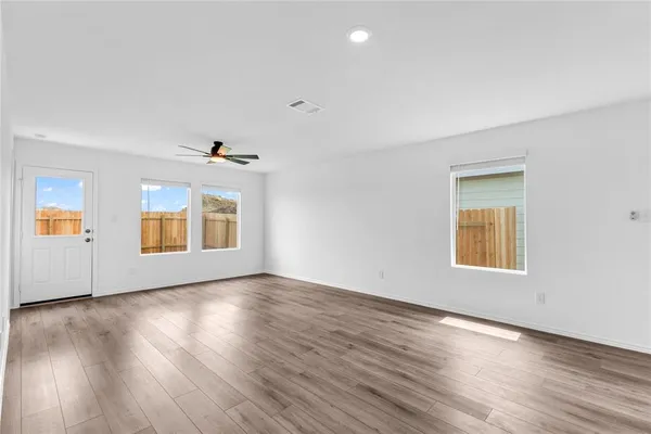 an empty room with wooden floor and windows