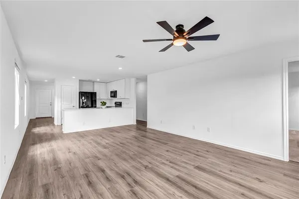 a view of empty room with wooden floor and ceiling fan