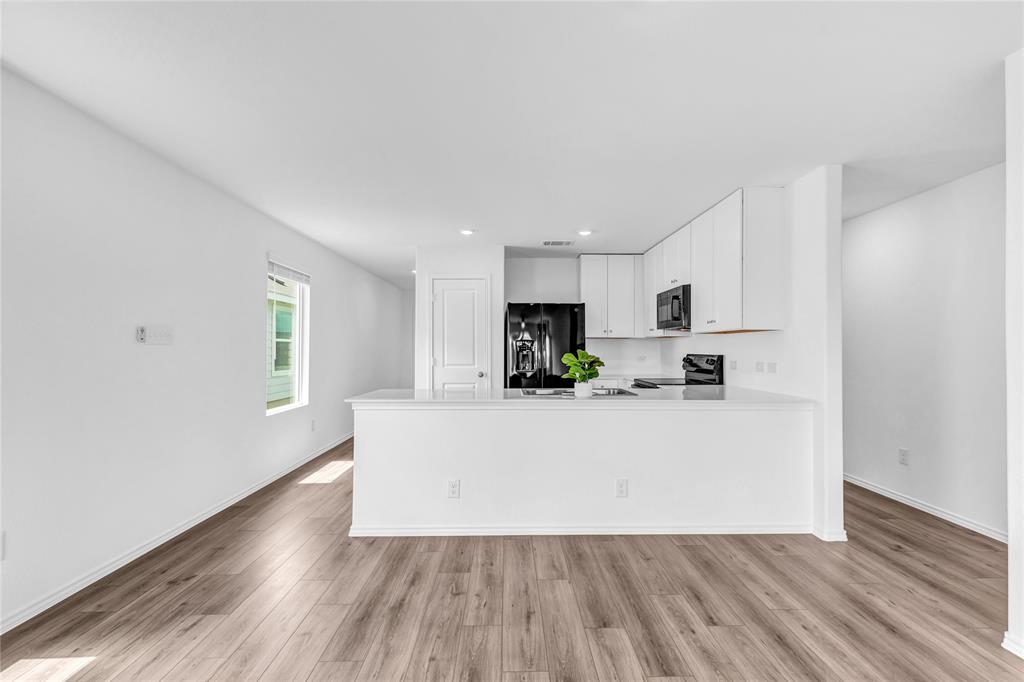 516 Rancho Del Cielo Loop Jarrell, TX 76537 - Photo 9 of 33 a living room with stainless steel appliances a wooden floor a large window and a wooden floor