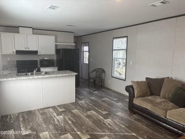 a living room with furniture a kitchen view and kitchen appliances