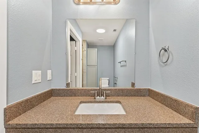 a bathroom with a granite countertop sink and a mirror