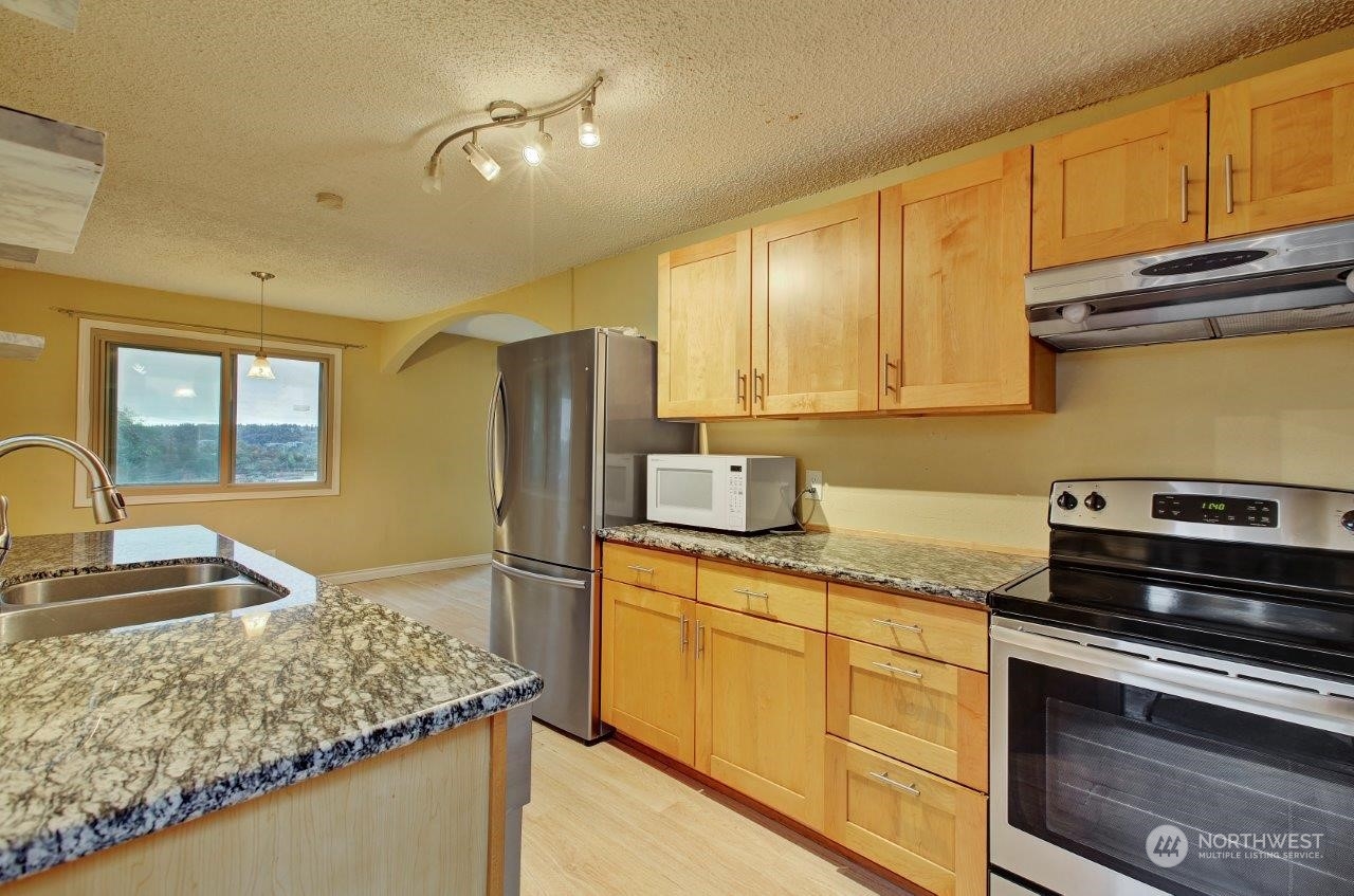 3906 South Pilgrim Street Seattle, WA 98118 - Photo 7 of 29 a kitchen with stainless steel appliances granite countertop a sink stove and refrigerator