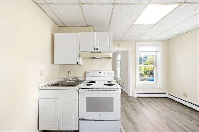 a kitchen with stainless steel appliances a white stove top oven cabinets and a window