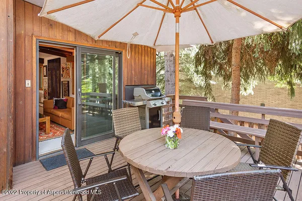 a view of a roof deck with table and chairs under an umbrella with wooden floor