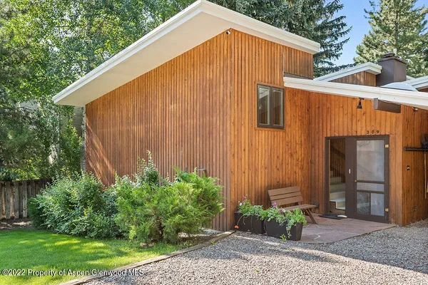 a backyard of a house with plants and large trees