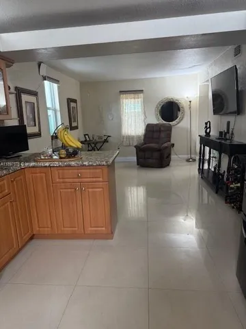 a living room with furniture a flat screen tv and kitchen view