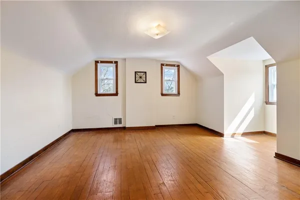 a view of an empty room with wooden floor and closet