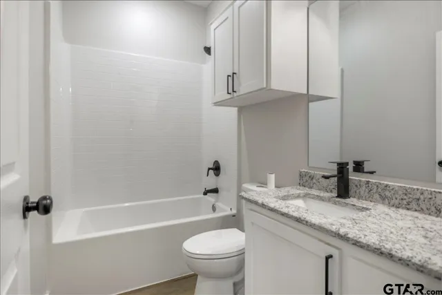 a bathroom with a granite countertop sink a toilet and bathtub