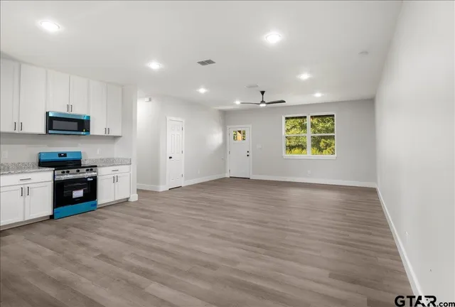 a view of an empty room with a window and a kitchen