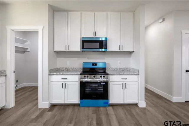 a kitchen with stainless steel appliances granite countertop a stove and a wooden floors