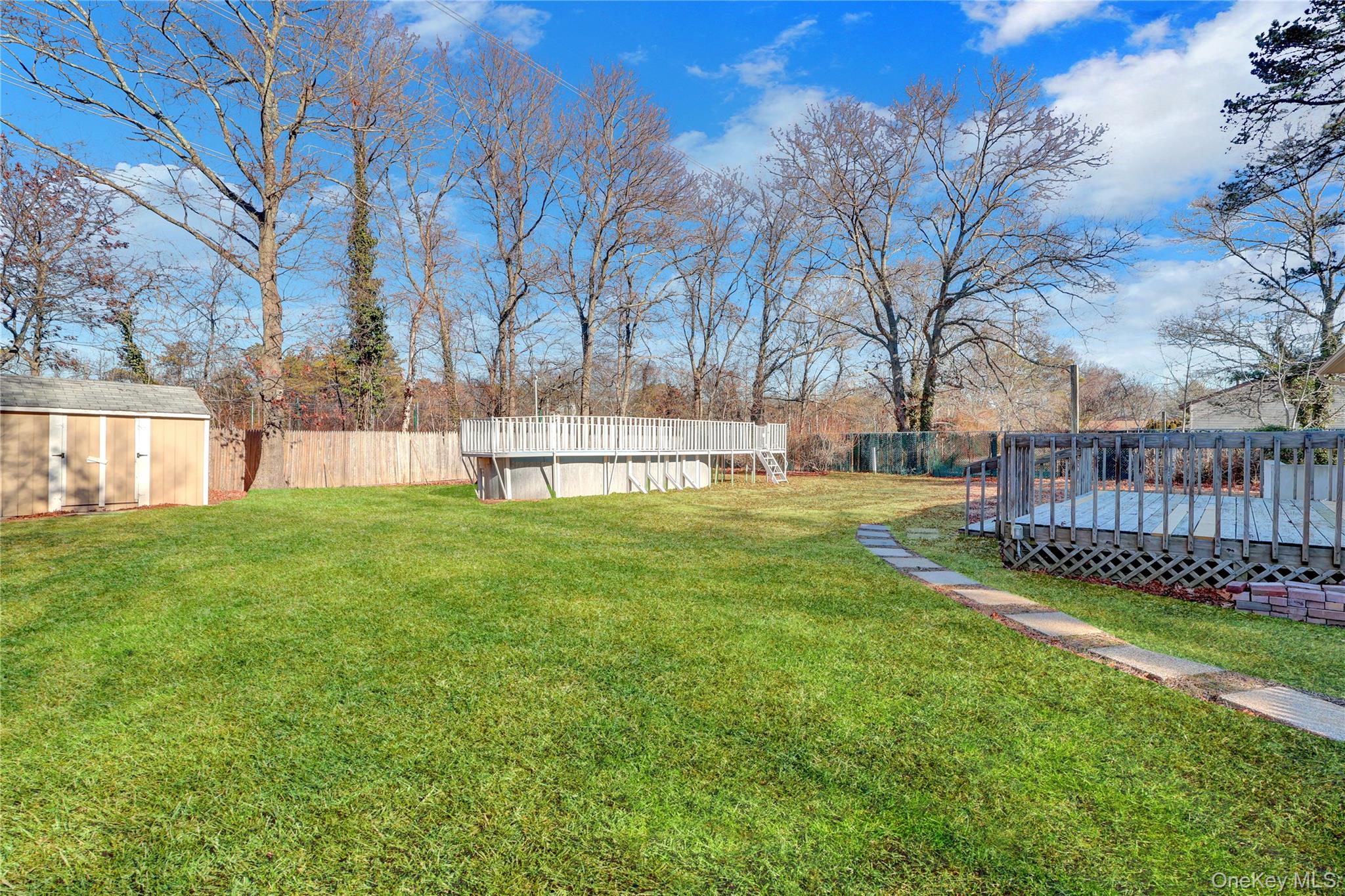 57 Middle Island Road Medford, NY 11763 - Photo 24 of 27 Fenced backyard featuring a wooden deck, a storage shed, and an empty pool
