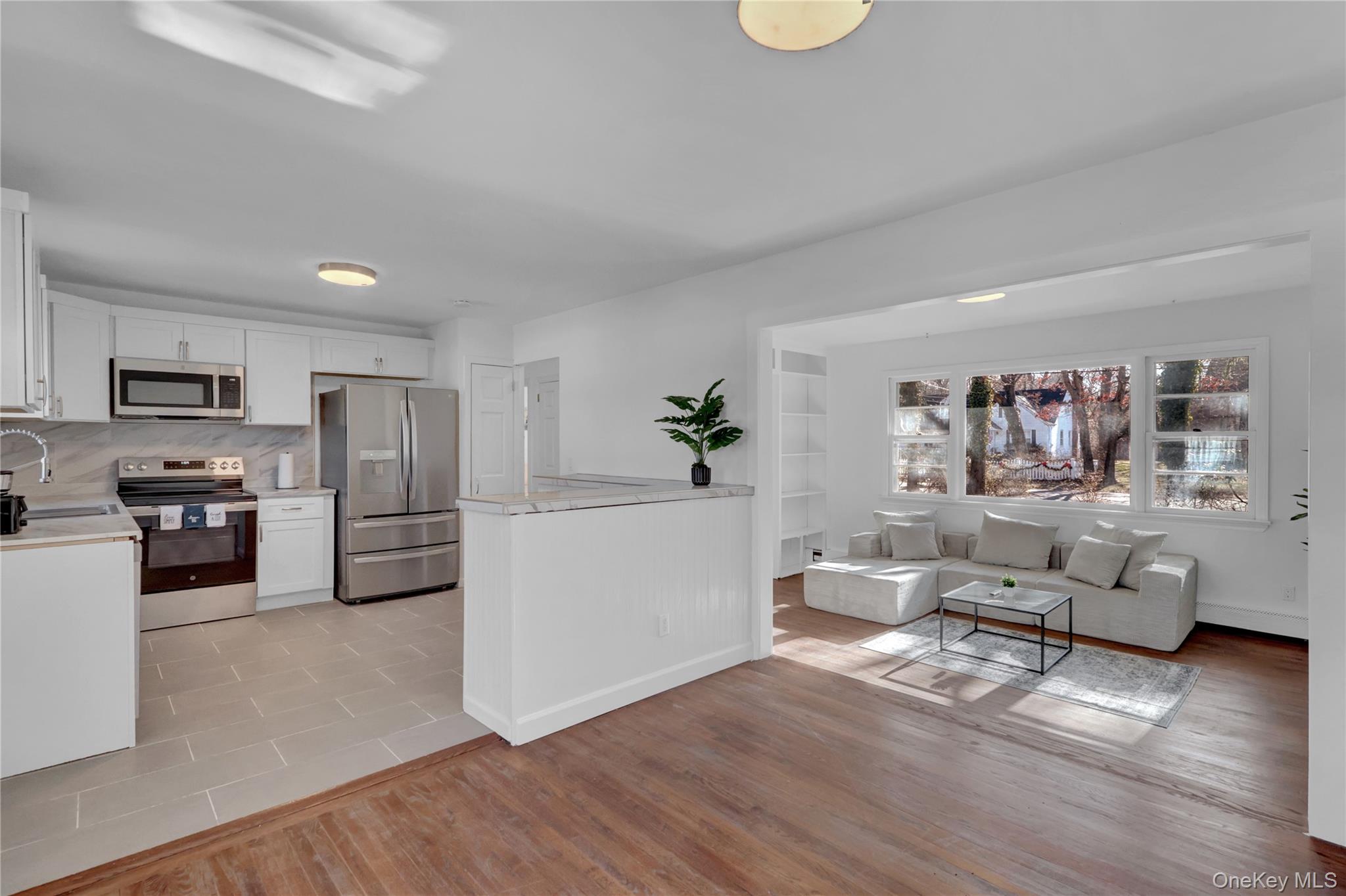 57 Middle Island Road Medford, NY 11763 - Photo 27 of 27 Kitchen featuring stainless steel appliances, white cabinetry, light wood-style floors, open floor plan, and decorative backsplash
