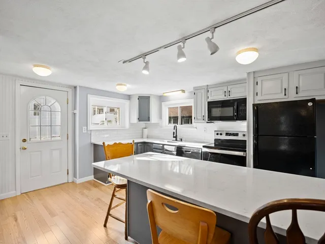 a kitchen with stainless steel appliances granite countertop a sink a stove a refrigerator cabinets and chairs