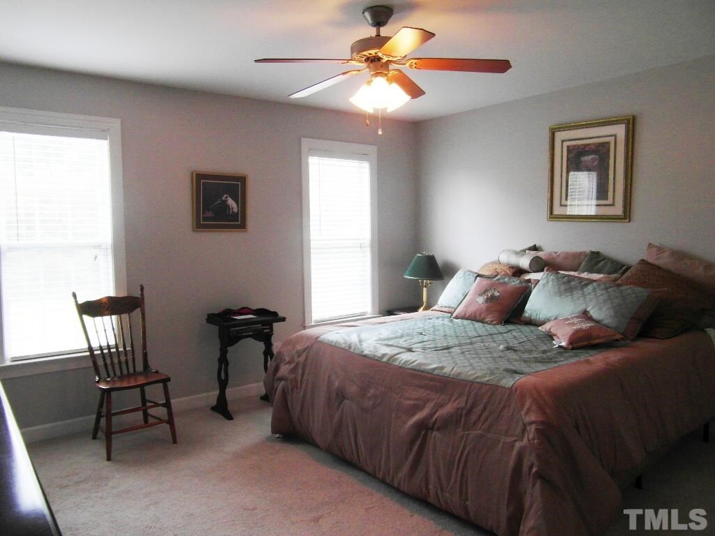 4936 Contender Drive Raleigh, NC 27603 - Photo 12 of 25 a bedroom with a bed and a chandelier