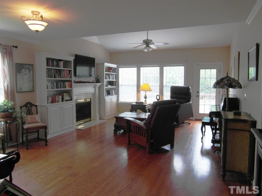 4936 Contender Drive Raleigh, NC 27603 - Photo 3 of 25 a living room with furniture a fireplace and a flat screen tv