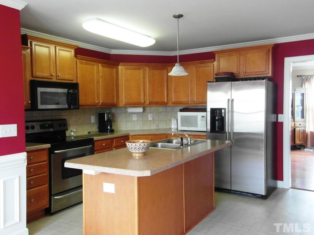 4936 Contender Drive Raleigh, NC 27603 - Photo 10 of 25 a kitchen with stainless steel appliances granite countertop a sink a stove and a refrigerator