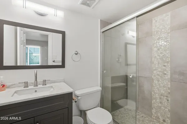 a bathroom with a granite countertop sink toilet a mirror and shower