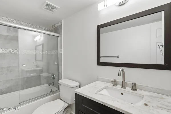 a bathroom with a bathtub shower sink vanity and toilet