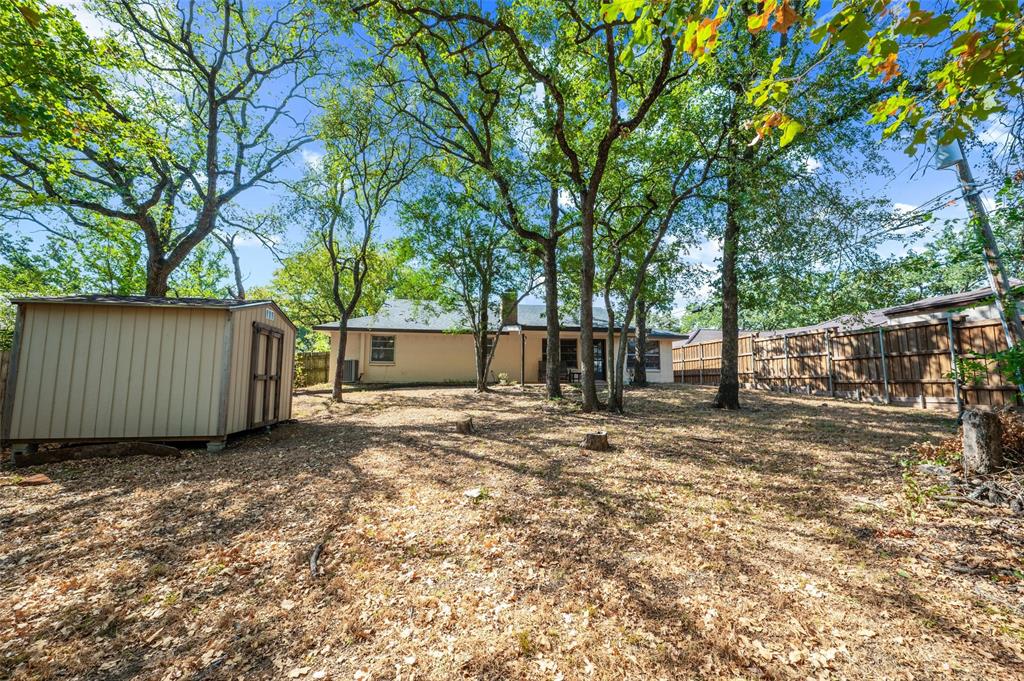 608 Ridgewood Circle Hurst, TX 76054 - Photo 32 of 38 Expansive rear yard featuring mature trees, a detached storage shed, and perimeter fencing