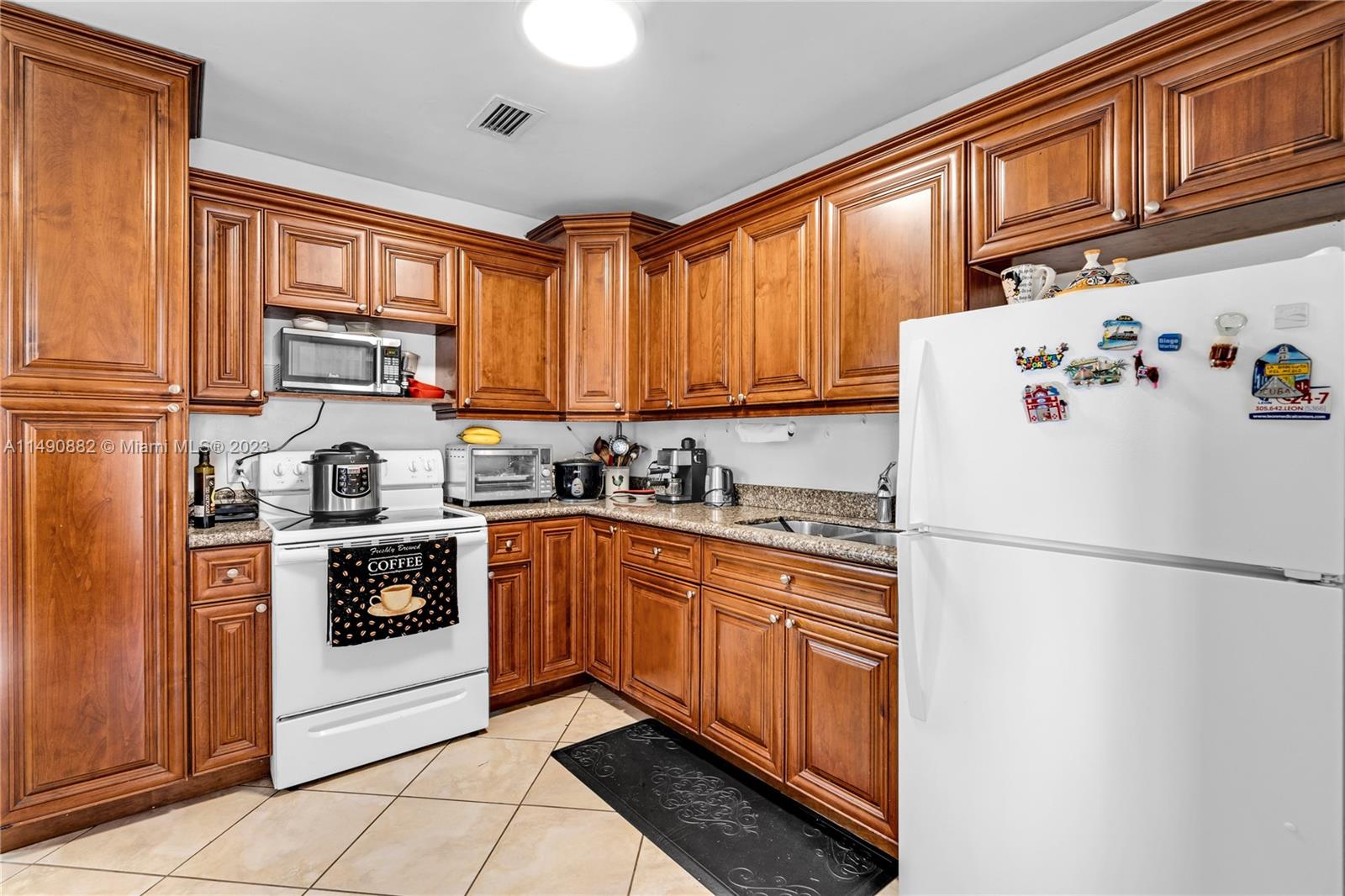3551 Frow Avenue Miami, FL 33133 - Photo 4 of 22 a white kitchen with stainless steel appliances granite countertop a refrigerator a stove a sink dishwasher and a refrigerator