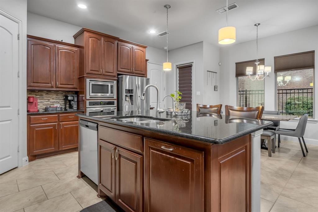 1229 Harris Hawk Way Arlington, TX 76005 - Photo 13 of 40 a kitchen with kitchen island granite countertop a sink stove and cabinets