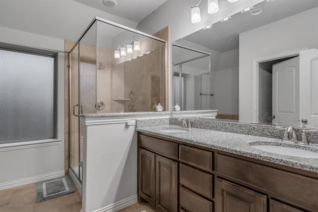 1229 Harris Hawk Way Arlington, TX 76005 - Photo 25 of 40 a bathroom with a granite countertop sink a mirror and a shower