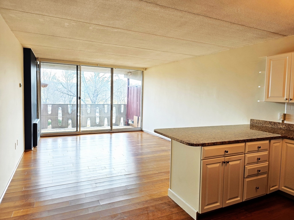 200 Swanton Street, Unit 318 Winchester, MA 01890 - Photo 3 of 9 a kitchen with white cabinets and wooden floor
