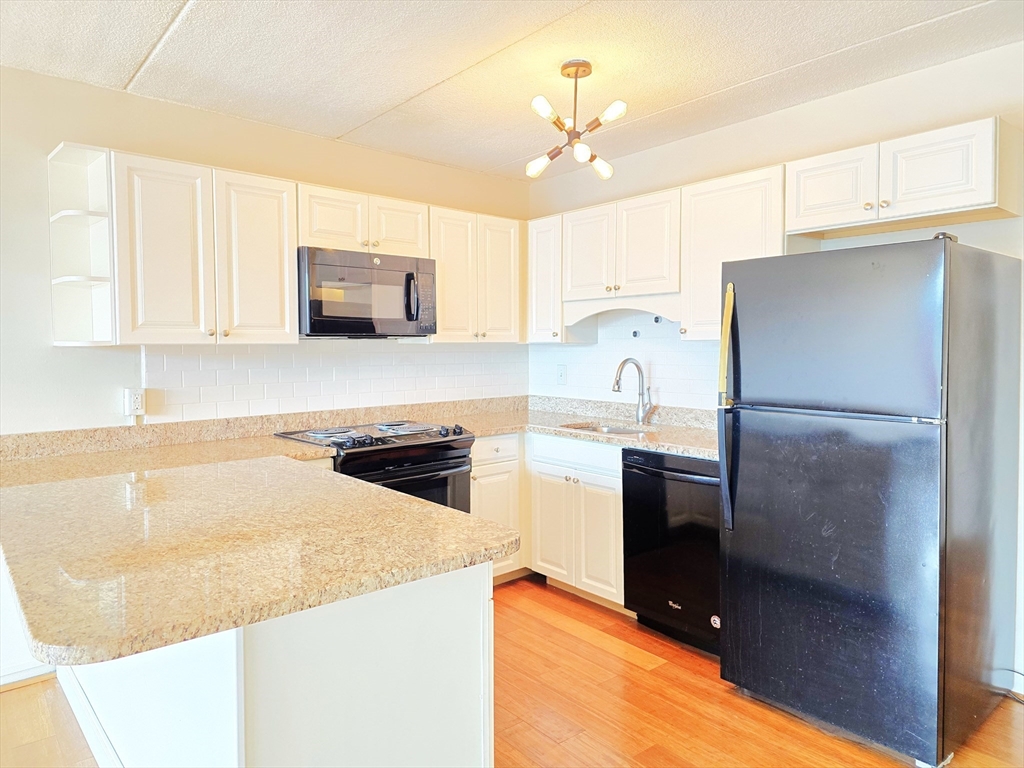 200 Swanton Street, Unit 318 Winchester, MA 01890 - Photo 4 of 9 a kitchen with granite countertop a refrigerator and a sink