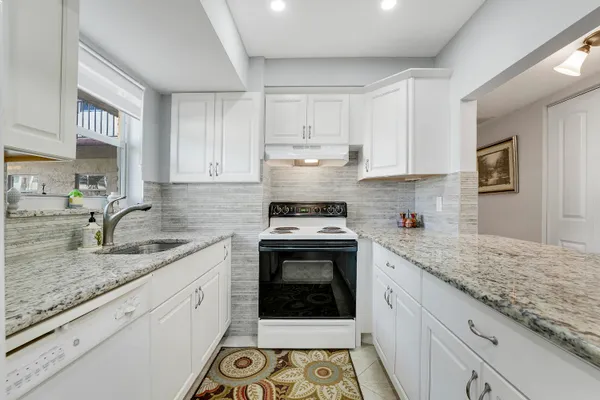 a kitchen with granite countertop a sink stainless steel appliances and white cabinets