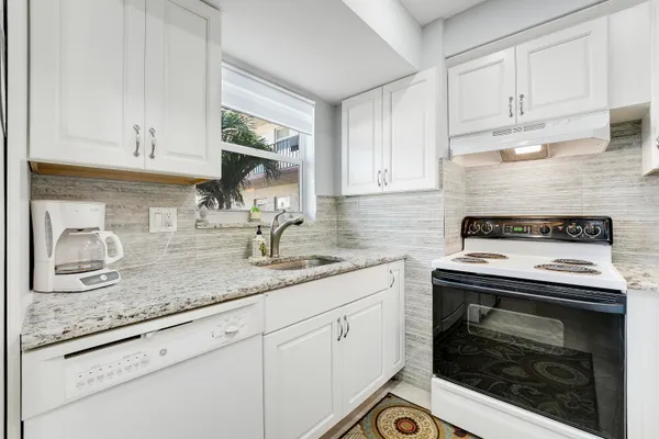 a kitchen with granite countertop white cabinets and white appliances