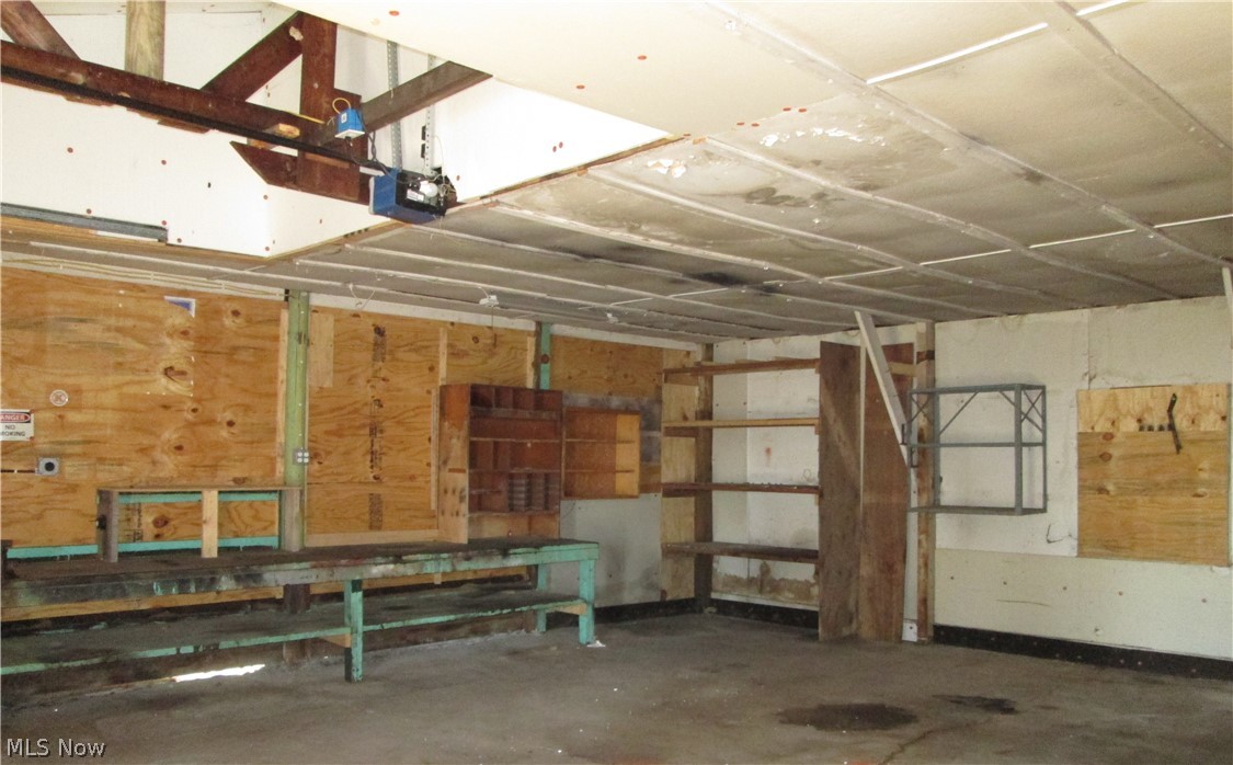 13096 Smith Road Wellington, OH 44090 - Photo 17 of 24 Garage space featuring concrete flooring, exposed ceiling beams, and plywood wall paneling