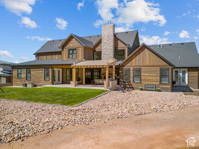 1192 East Ashdown Road Cedar City, UT 84721 - Photo 15 of 96 Wood siding exterior with a dark shingle roof, stone chimney, and a covered patio with a wood pergola