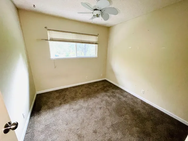 an empty room with a ceiling fan and a window