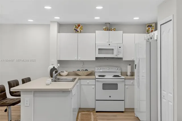 a kitchen with a sink a stove a refrigerator and white cabinets