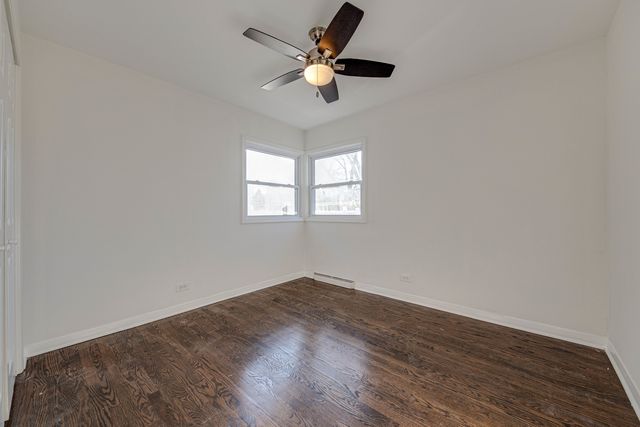 an empty room with wooden floor chandelier fan and windows