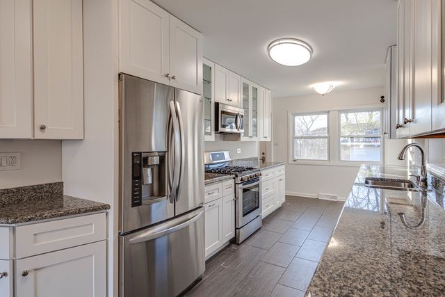 a kitchen with granite countertop a refrigerator stove top oven and sink