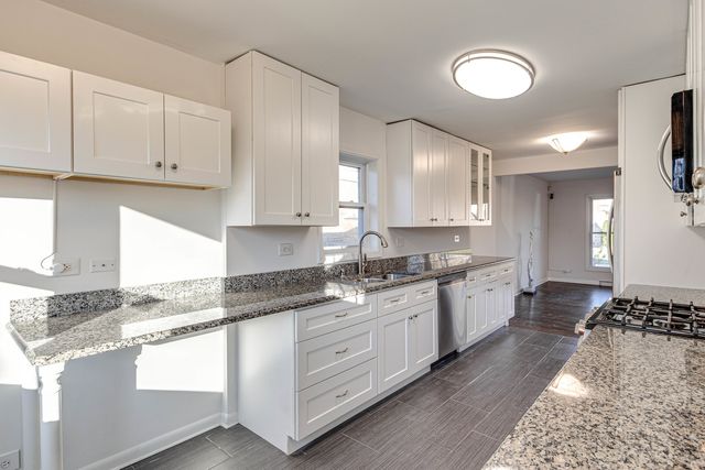 a large kitchen with granite countertop a sink stainless steel appliances white cabinets and a granite counter tops