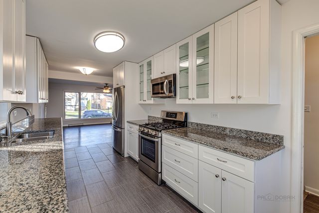 a kitchen with granite countertop a stove sink and cabinets