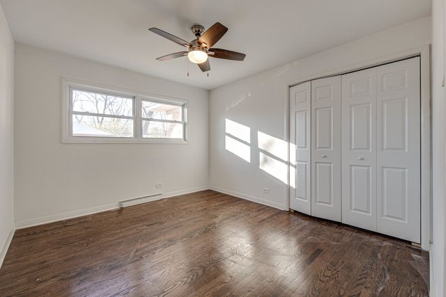 an empty room with wooden floor chandelier fan and windows