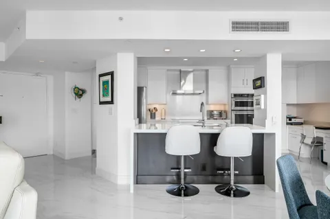 a kitchen with stainless steel appliances refrigerator dining table and chairs